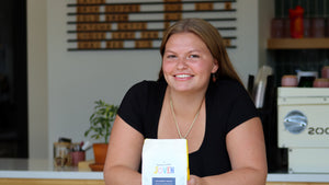 a girl, frankie, leans on a standing table at sparrows coffee with a bag of Joven Colombia Cauca